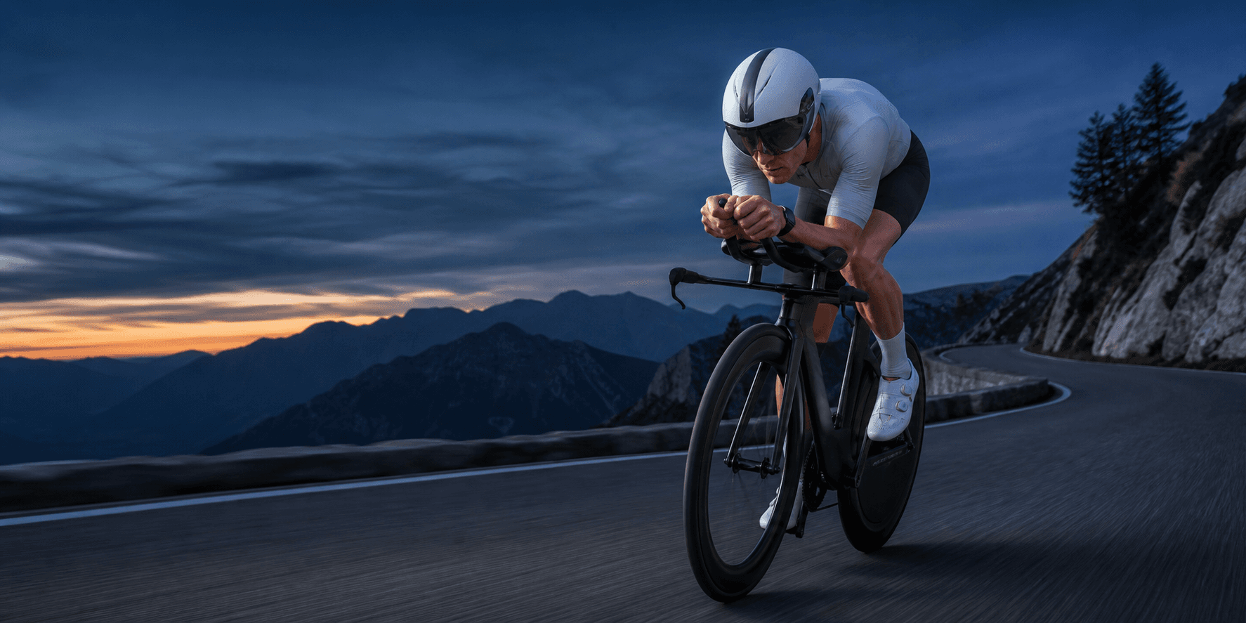 Triathlet fährt in aerodynamischer Position auf einer trockenen Bergstraße